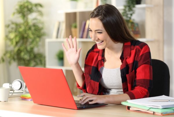 smiling young female student waving at computer