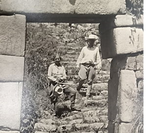 A black and white photo of two people sitting on a stone staircase.