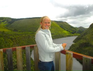 The Experiment in International Living student standing on wooden balcony. Behind her are green mountains and a river.