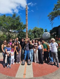 An Experiment in International Living group of students standing in front of a tall stone monument at the equator.