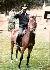 A man in military uniform riding a horse and saluting.
